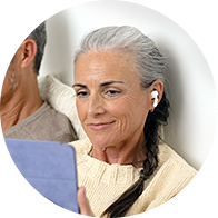 Senior woman wearing a modern hearing aid while using a tablet