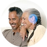 Couple relaxing on a couch, one wearing a hearing aid