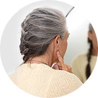 Senior woman touching her ear while looking in a mirror