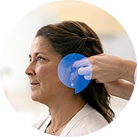 Donna durante il posizionamento di un apparecchio acustico sull'orecchio.