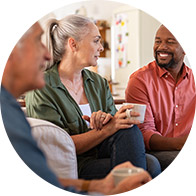 Older woman holding a cup, appearing to have difficulty hearing during a group conversation.