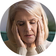 Woman with blonde hair holding her head in her hands, expressing stress or discomfort.