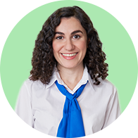 Professional woman with curly hair wearing a blue tie and white shirt against a green background.