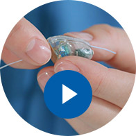 Immagine di una mano che sostituisce la batteria di apparecchio acustico