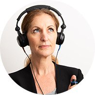 Une personne, portant un casque audio noir, effectue un test auditif dans un contexte clinique. Elle tient un bouton d’évaluation, typique de consultations chez un audioprothésiste spécialisé dans les aides auditives.