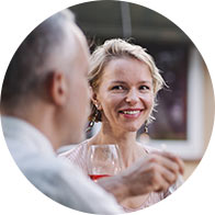 Pessoas conversando e desfrutando de um jantar ao ar livre com taças de vinho.