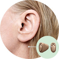 [GEN] A close-up of a woman's ear fitted with a discreet, in-the-ear hearing aid. Nearby, a detailed inset displays the device's design, highlighting its compact size, ideal for personalized hearing care.