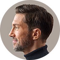 En person med kort, velsoigneret hår set fra siden, iført en mørk højhalset trøje. Fokus er på øret, potentielt relateret til høreapparater eller høretests i en høreklinik.