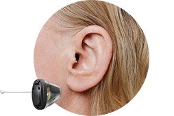 Een oor met een discreet in-ear gehoorapparaat van Oticon, geplaatst in een natuurlijke huidtintomgeving. De context benadrukt gehoorzorg en gepersonaliseerde oplossingen bij een audicien of hoorwinkel.