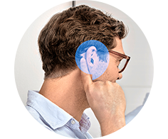 A man adjusts a behind-the-ear hearing aid within a clinical setting. He is positioned sideways, emphasizing the hearing device, likely suggesting professional services like hearing tests or audiologist consultations for improved hearing.