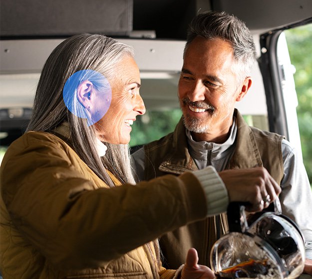 A couple interacting while the woman pours coffee, with a focus on her discreet hearing aid.