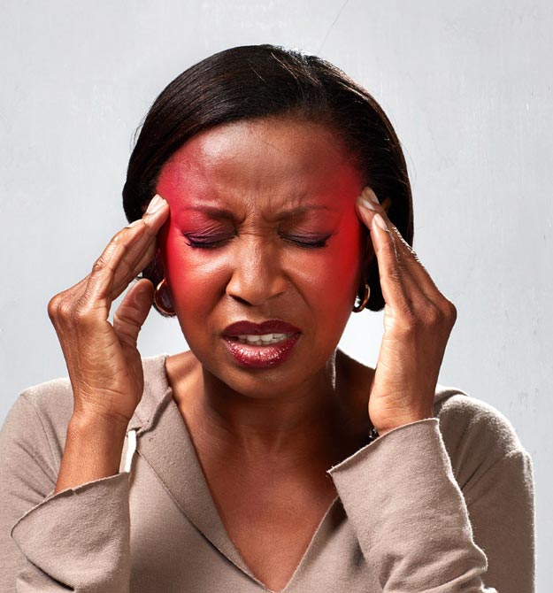 Vrouw met rode blos op haar wangen die haar handen tegen haar voorhoofd houdt, mogelijk last van hoofdpijn of stress.