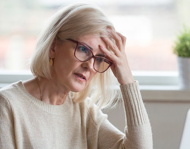 woman with blonde hair holding her head indoors