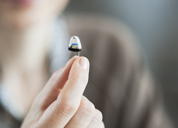 Image show hand holding a hearing aid