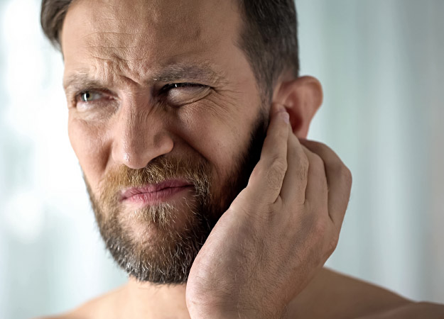 Man met tinnitus houdt zijn hand tegen zijn oor