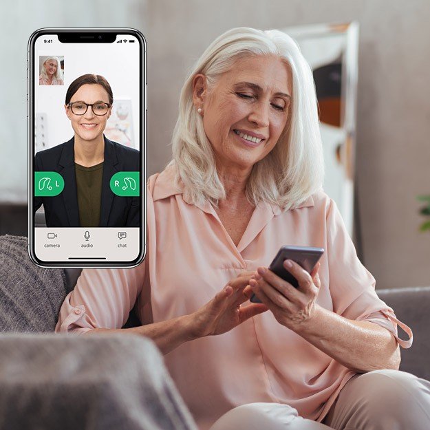 Donna anziana utilizza uno smartphone con un’applicazione per il controllo dell’audio degli apparecchi acustici.