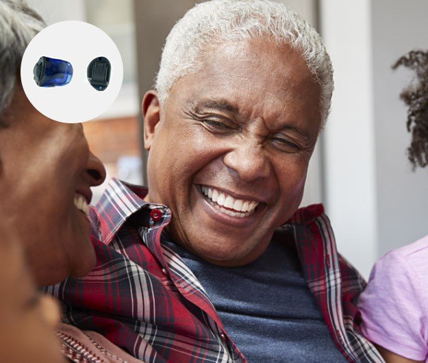 Un appareil auditif intra-auriculaire bleu (modèle discret) est montré en gros plan dans un cercle. En arrière-plan, des personnes souriantes sont assises dans un cadre familial. Aucun texte présent.