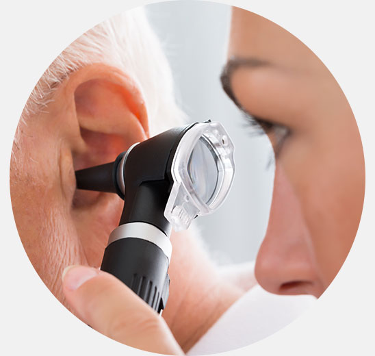 Un audiologiste examine l’oreille d’un patient à l’aide d’un otoscope dans un cabinet spécialisé en soins auditifs, tel qu’Audika, pour évaluer la nécessité d’appareils auditifs modernes.