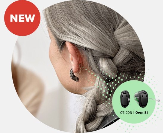 Woman with gray braided hair wearing an Oticon Own SI hearing aid.