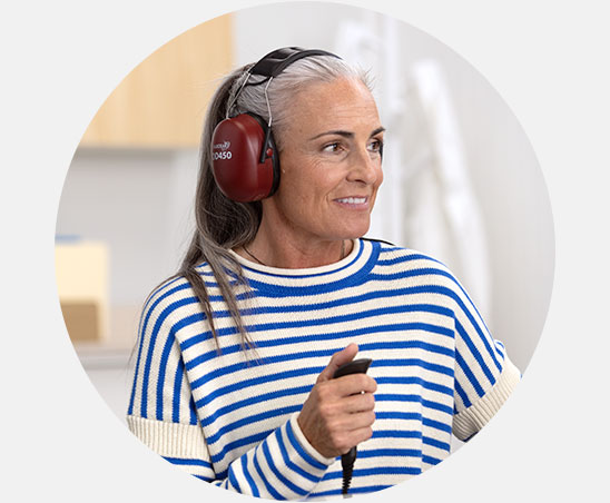 Woman wearing headphones and holding a response button during a hearing test