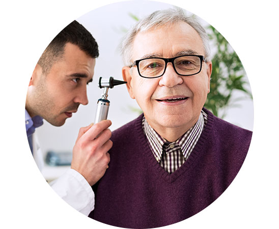 Audiologist performing ear examination on an older man experiencing age-related hearing loss