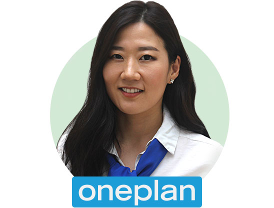 Audiologist wearing a white blouse with a blue scarf, representing Oneplan hearing care services.