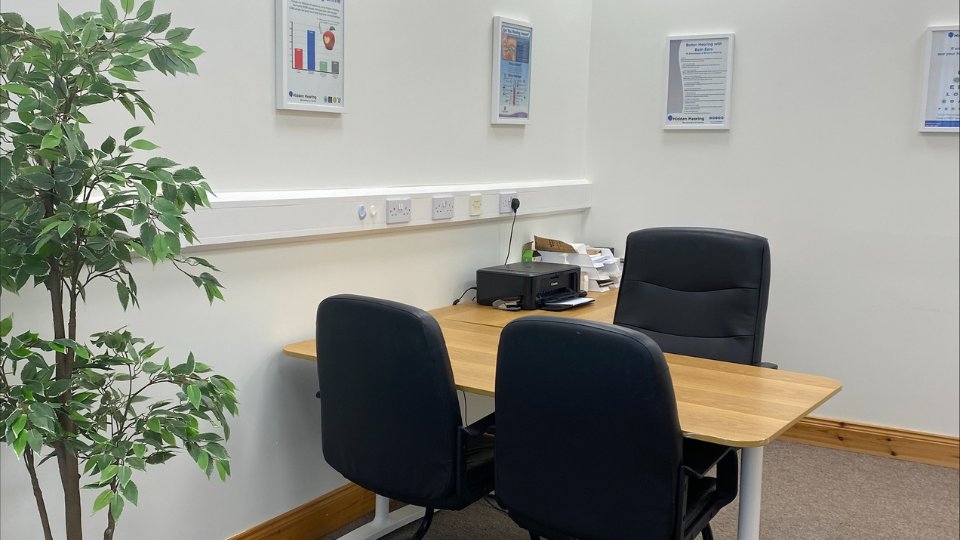 hearing aids consultation room in Donegal featuring chairs, a desk, and informational posters