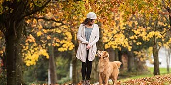 Femme marchant avec son chien dans un parc en automne.
