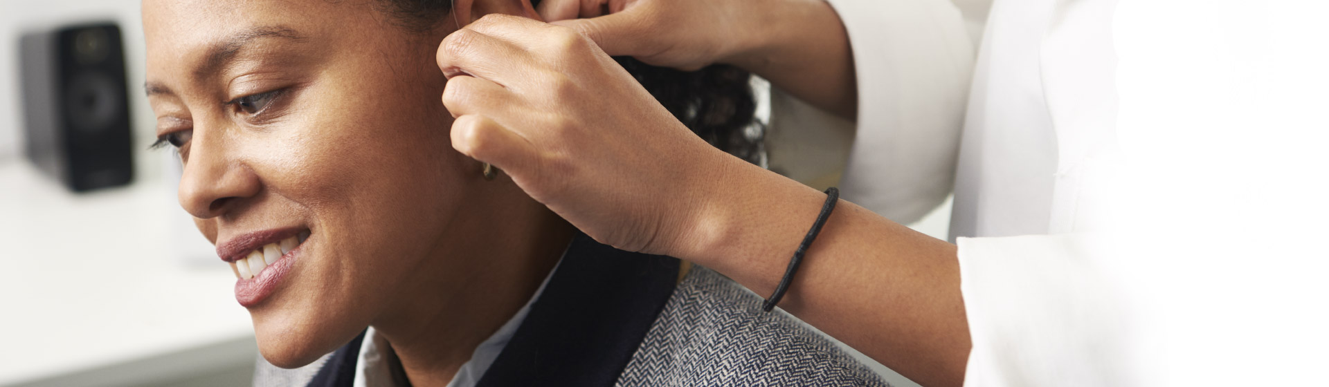 L’image montre un audiologue qui met des appareils auditifs dans l’oreille d’une femme