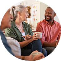 Conversation informelle entre plusieurs personnes tenant des tasses dans un salon lumineux.