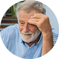 Homme âgé en chemise bleue se tenant la tête.