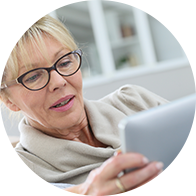 Femme assise sur un canapé utilisant une tablette dans un environnement lumineux.