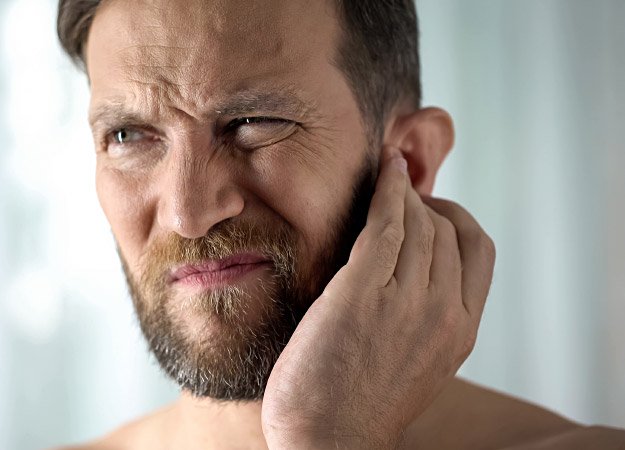 Un homme tenant son oreille en raison de symptômes liés aux acouphènes.