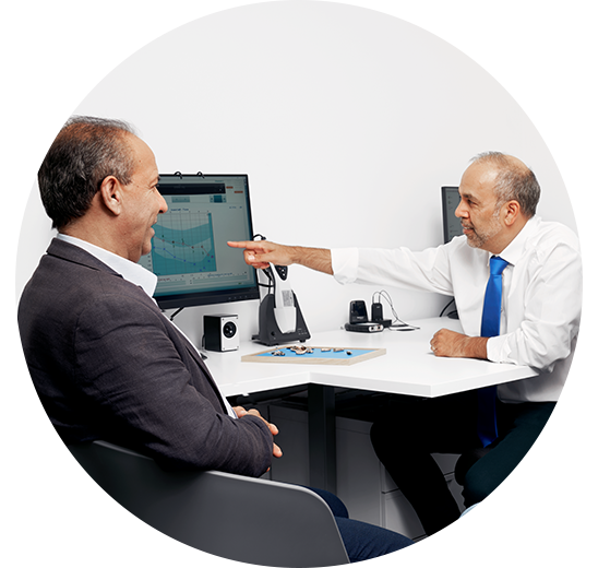 Un homme discute avec un audiologue qui lui montre un audiogramme sur un écran pendant une consultation.