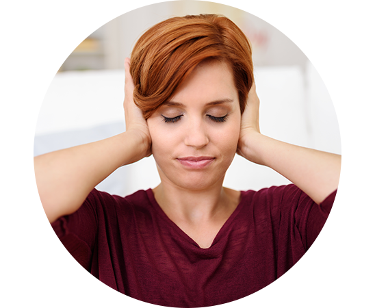 Une femme aux cheveux roux se couvre les oreilles avec ses mains, exprimant une gêne sonore.