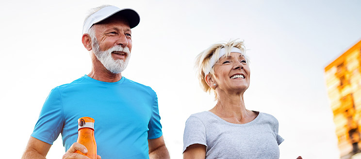 Couple senior en pleine séance de jogging en extérieur par une journée ensoleillée.
