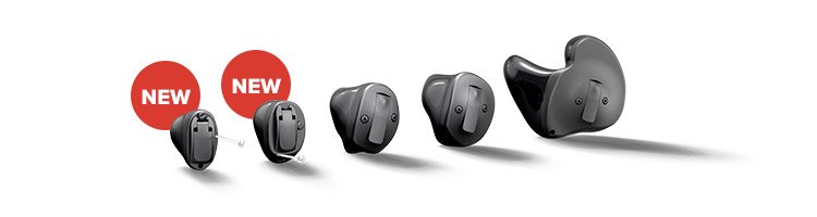 Cinq aides auditives Oticon intra-auriculaires noires alignées, deux marquées 'NEW' en rouge. Elles varient en taille, illustrant des options personnalisées dans un contexte de soins auditifs innovants.