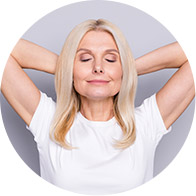 Femme heureuse aux cheveux blonds, posant avec les mains derrière la tête.