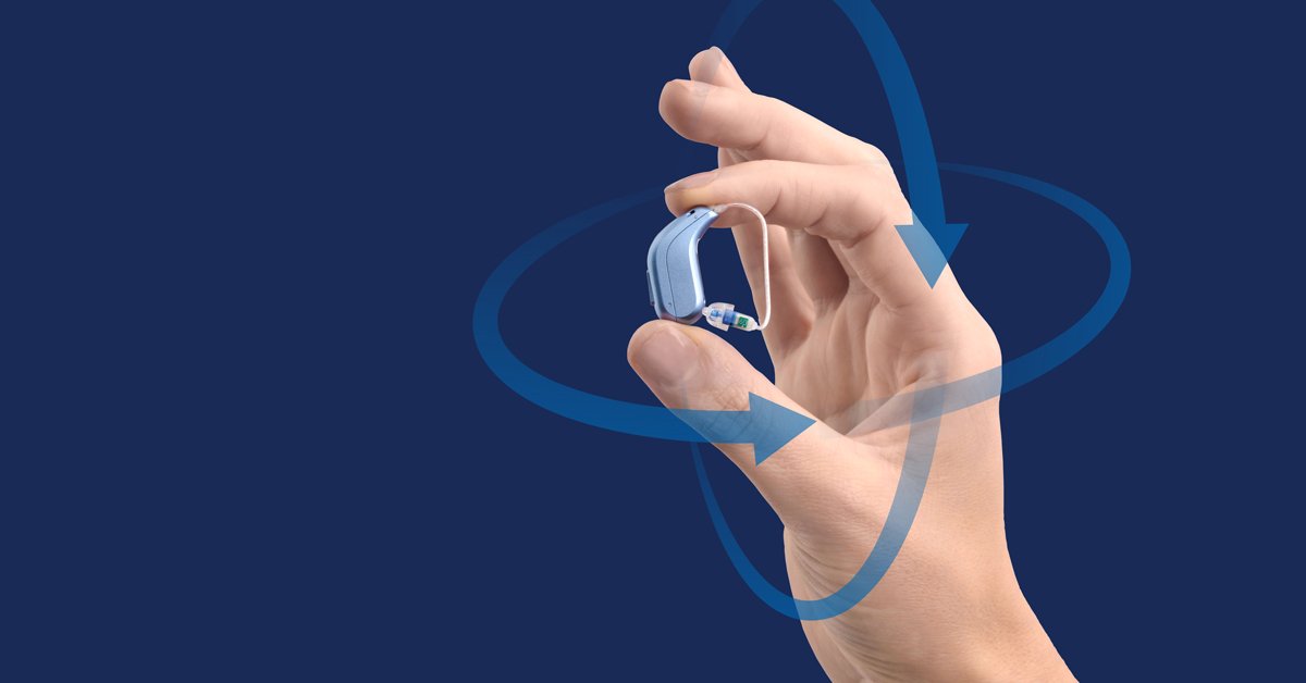 Una mano tiene un apparecchio acustico blu con design raffinato, circondato da frecce curve traslucide che evocano movimento su sfondo blu scuro, simbolo di tecnologia avanzata.