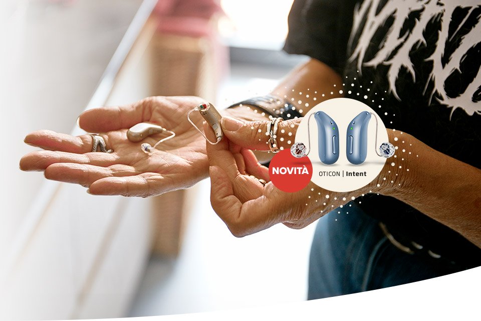 Mani di una persona reggono apparecchi acustici; a destra, un cerchio mostra due modelli moderni di Oticon Intent con la scritta ’NOVITÀ OTICON | Intent’. Sfondo luminoso in un contesto domestico.