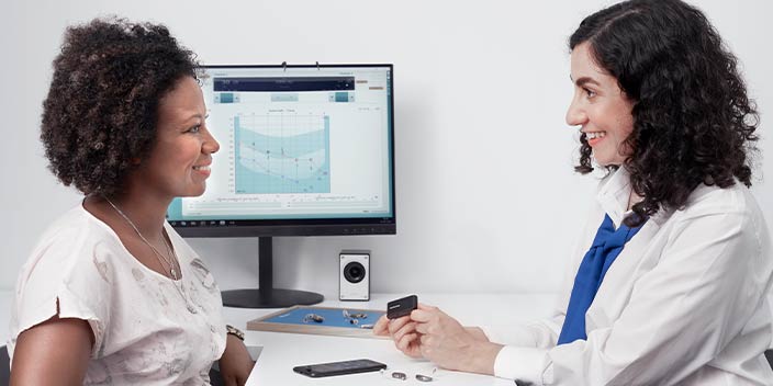 Audioloog die hoortoestelopties en accessoires bespreekt met een klant