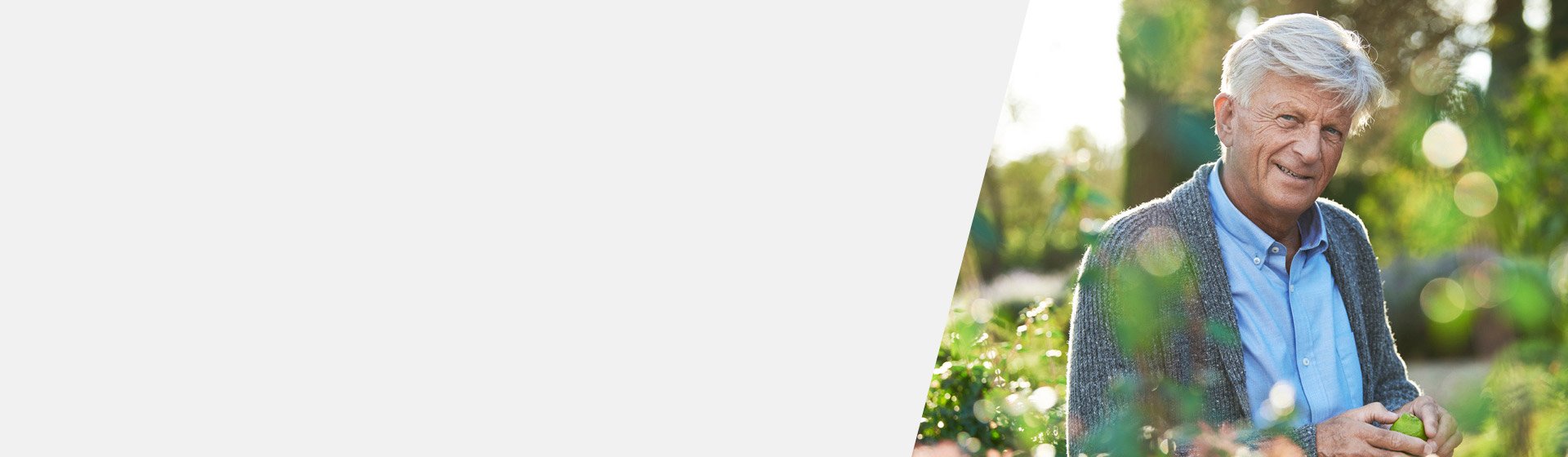 Glimlachende oudere man met sensorineuraal gehoorverlies in een groene tuinomgeving