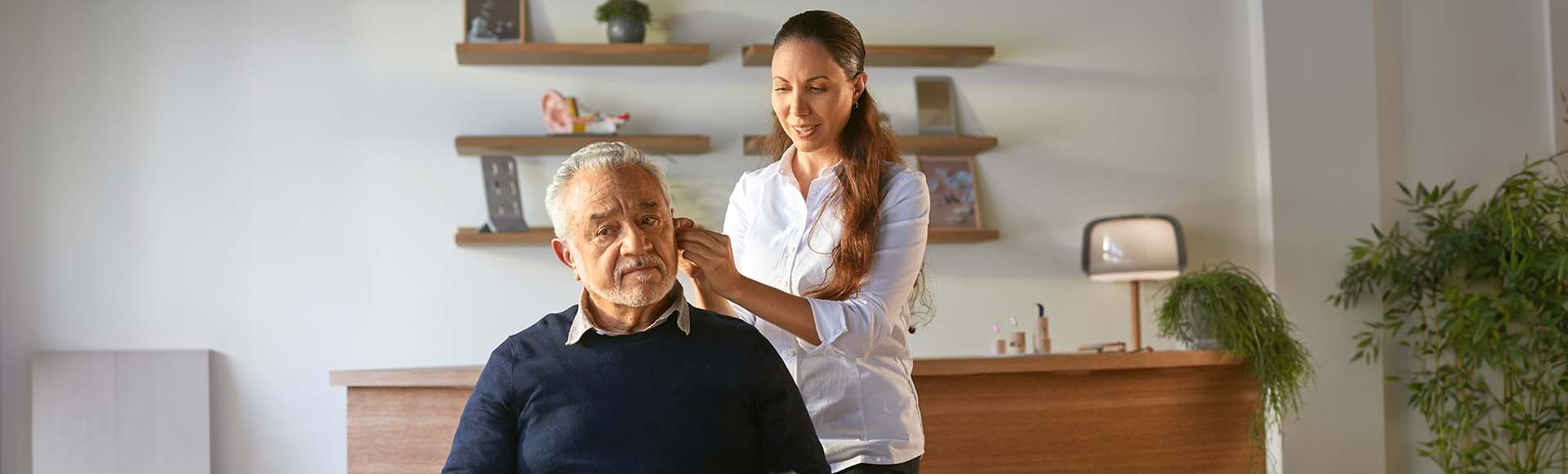 Man krijgt hulp bij het aanpassen van zijn hoortoestel in een moderne gehoorzorgpraktijk.