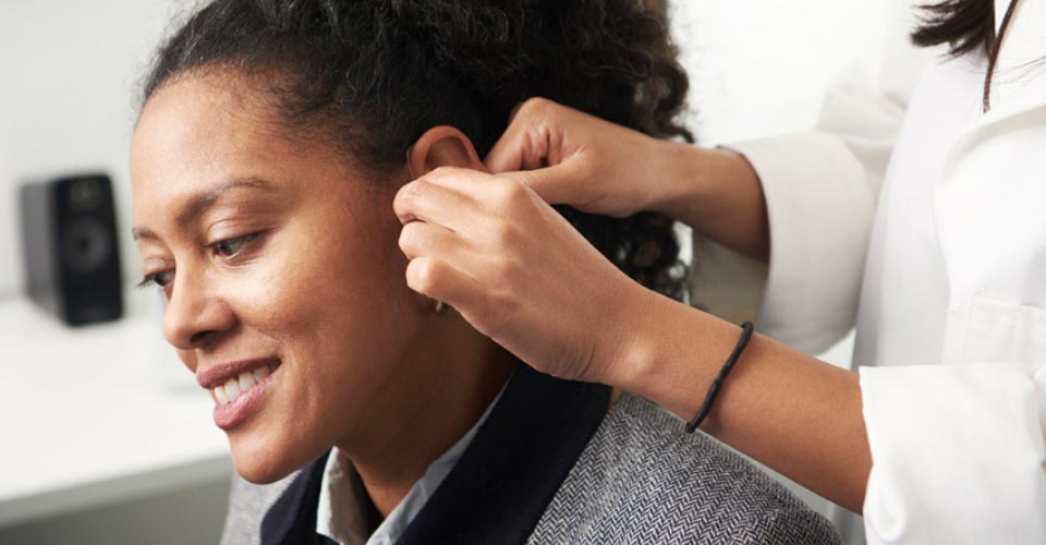 Afbeelding van vrouw die een reparatie/bijstelling van haar hoorapparaten laat doen