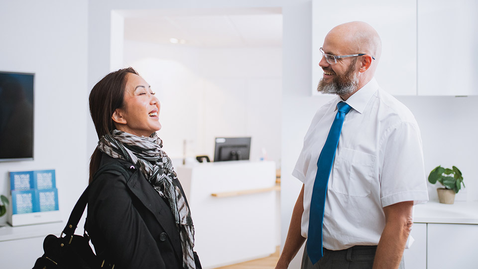 Afbeelding van audioloog en vrouw glimlachend bij een hoorcentrum 