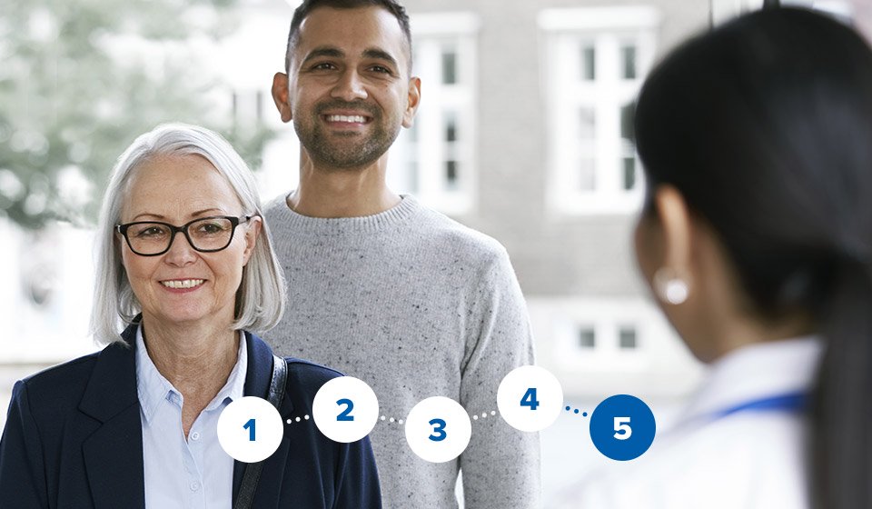 Audioloog verwelkomt man en vrouw in hoorcentrum.