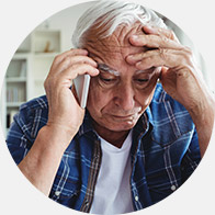 Oudere man die zijn hoofd vasthoudt terwijl hij aan de telefoon praat.