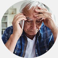 Oudere man die zijn hoofd vasthoudt terwijl hij aan de telefoon praat.