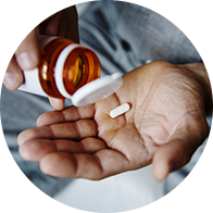 Hand houdt een pil vast die uit een medicijnfles wordt geschonken