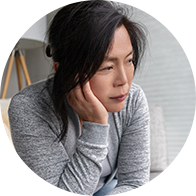 Vrouw die zich triest voelt, in een grijze trui zittend in een huiselijke omgeving.